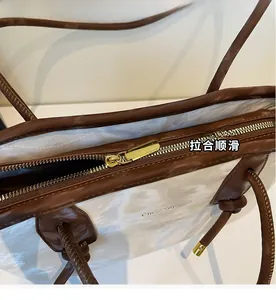 Close-up of smooth golden metal zipper detail on white and brown vintage tote bag
