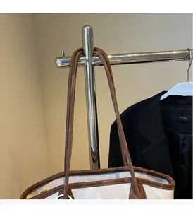 Detail of white tote bag featuring long brown leather handles and reinforced stitching