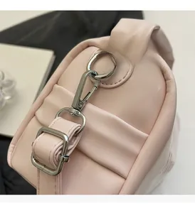 Detail of silver metallic buckle and gathered leather texture on a pink shoulder bag