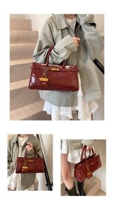 Detail of burgundy patent leather handbag with gold metal clasp and mini coin purse