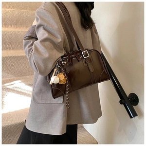 Detail of brown patent leather tote bag with silver buckle and mini baseball charms
