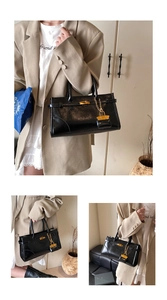 Close-up of black glossy leather handbag with gold metal clasp and mini lock charm