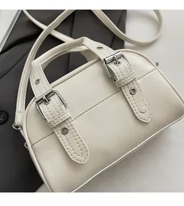 Détail du sac Boston crème montrant le similicuir texturé et les boucles métalliques