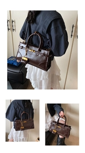 Detail of deep brown glossy leather handbag with gold metal lock and chain strap