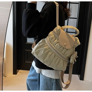 Detail of beige pleated backpack with wavy handle and matching mini coin purse hanging on side