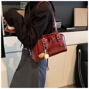 Detail of dark red glossy leather tote with baseball glove charm and metal buckles