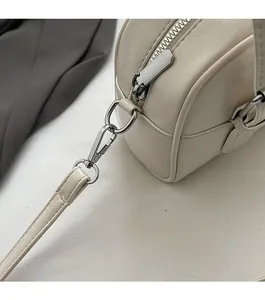 Gros plan du sac bandoulière crème avec anneaux en D argentés et cuir synthétique de qualité