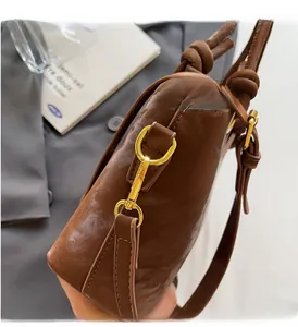 Makro-Detail der glänzenden braunen Ledertasche mit goldenen Beschlägen und Knotendesign