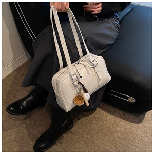 Detailed shot of a white retro soft leather tote bag with a baseball charm on a sofa