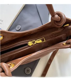 Detail eines glatten goldenen Metall-Reißverschlusses und brauner Lederstruktur der Handtasche