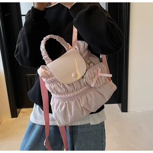 Pink pleated nylon backpack with matching bow pendant shown on model for size scale