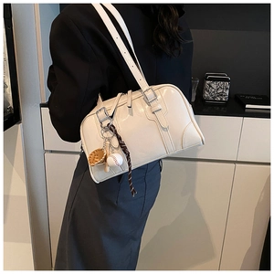Detail of cream leather tote bag featuring silver buckles and sporty charms on shoulder strap