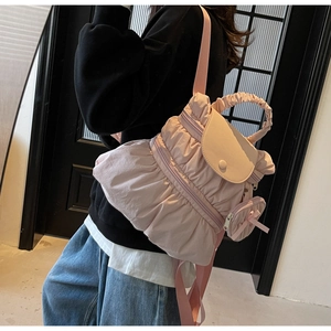 Detail showing the light pink pleated nylon fabric and cute bow charm on the backpack