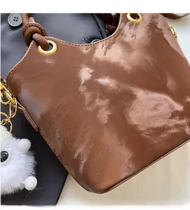 Detail der dunkelbraunen Handtasche mit Marmortextur, Goldring-Griff und Plüsch-Anhänger