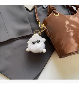 Detailansicht weißer Monster-Plüschanhänger mit großen Augen an brauner Ledertasche
