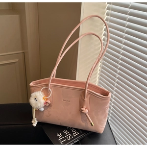 Detail of pink faux leather tote bag with brand embossing and fluffy charm accessory