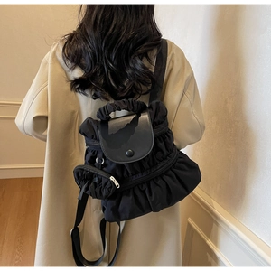 Détail d'un sac à dos plissé noir avec une mini pochette assortie et une poignée chic