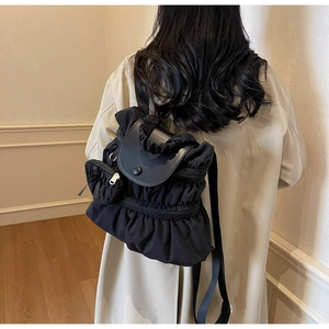 Close-up of black nylon pleated backpack with leather flap and magnetic buckle detail