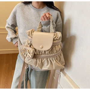 Detail of khaki pleated nylon backpack with ruffled trim and matching round coin purse charm