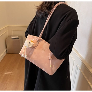Detail of pink glossy patent leather tote bag with soft plush charm and shoulder strap