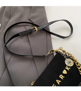 Close-up of matte black crossbody bag with gold chain and adjustable leather strap