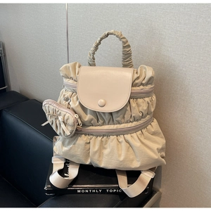 Close-up of beige pleated nylon backpack with leather flap and mini pouch attachment