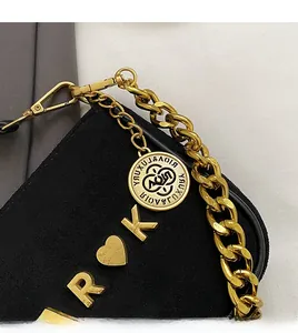Close-up of black suede bag with gold chain strap, metal heart and letter charms