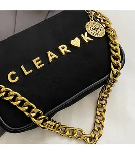 Detail of matte black suede chain bag showing gold CLEAR letters and heavy Cuban link strap