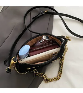 Interior view of minimalist black crossbody bag with gold chain and brown fabric lining