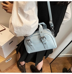 Détail du sac Boston bleu clair en cuir verni avec boucles en métal et fini brillant
