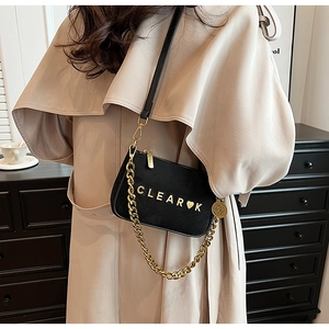 Detail of matte black crossbody bag with gold CLEAR-K logo and chunky chain strap