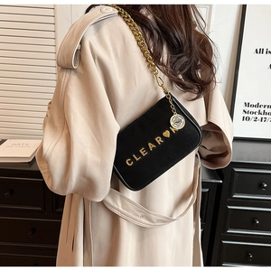 Detail of black crossbody bag with gold chunky chain and CLEAR lettering logo