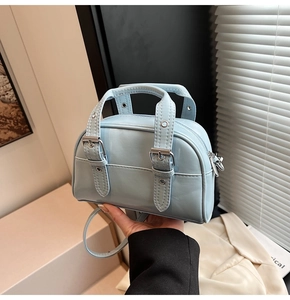 Détail du mini sac Boston en cuir verni bleu clair avec boucles argentées et poignée