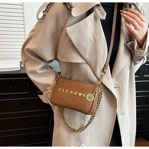 Detail of a brown matte shoulder bag featuring gold CLEAR K hardware and metal chain strap