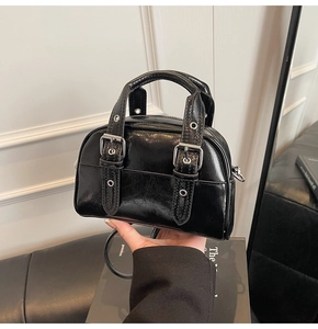 Détail d'un sac à main en cuir noir brillant avec boucles argentées et sangle