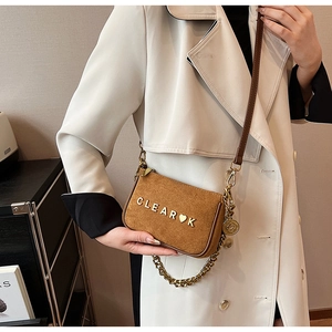 Detail of brown suede crossbody bag with gold chain strap and CLEAR heart metallic logo
