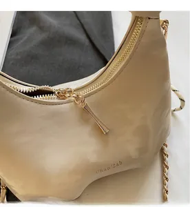 Detailed close-up of smooth gold zipper and beige leather texture on crescent bag