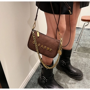 Detail of dark brown suede crossbody bag with gold CEAR K lettering and chunky chain strap