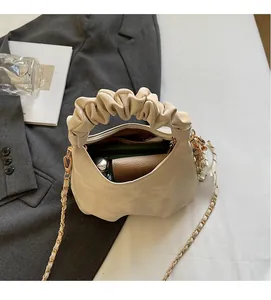 Detail of beige pleated handbag with gold chain strap showing spacious interior capacity