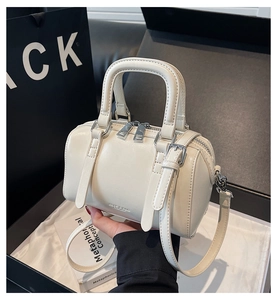 Gros plan du sac Boston crème minimaliste avec détails argentés et bandoulière