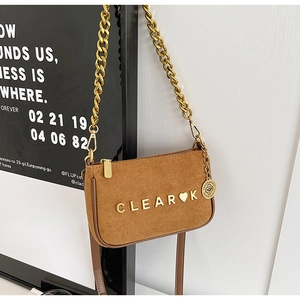 Detail of matte brown crossbody bag with gold CLEAR K hardware and metal chain strap