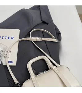 Détail du sac Boston crème avec bandoulière réglable et doubles poignées rondes