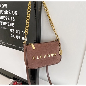 Detail of brown suede crossbody bag with gold chain strap and metal letter logo