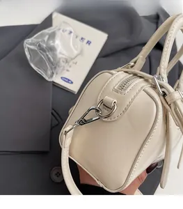 Détail de la fermeture éclair argentée et coutures de ce sac Boston blanc cassé