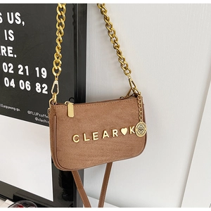 Detailed macro view of the brown suede surface with gold CLEAR K lettering and chain