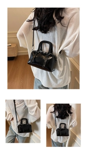 Détail d'un chic sac Boston noir brillant avec ferrures argentées et bandoulière