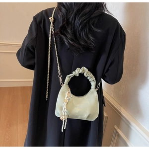 Detail of light green cloud bag with pleated handle and golden chain on a model