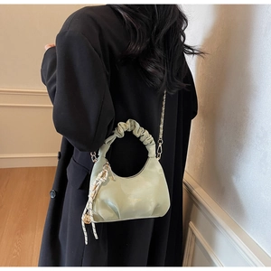 Detail of light green ruched dumpling bag with gold chain and striped silk scarf