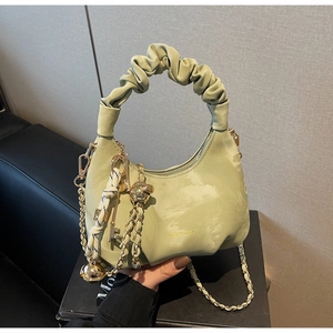 Detail of light green pleated handbag with golden chain strap and decorative charms