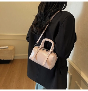 Détail du sac Boston rose clair avec poignées porté par un mannequin en blazer noir